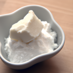 Moisturizing shea butter in white bowl on wooden table