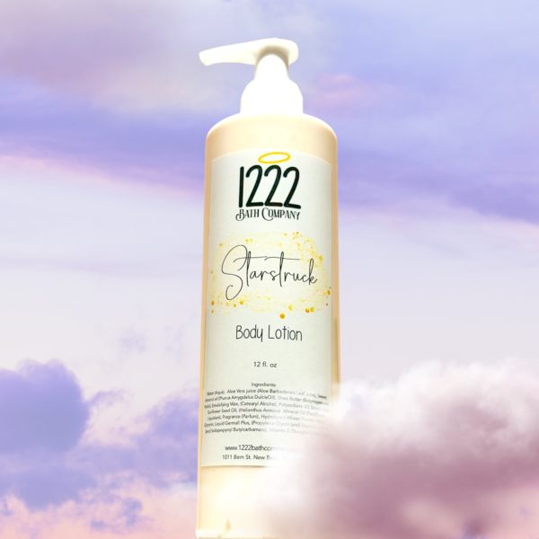 Bottle yellow lotion 12 oz with white pump. Label has 1222 bath co. With a halo over numbers. Lotion set amongst pink purple clouds.